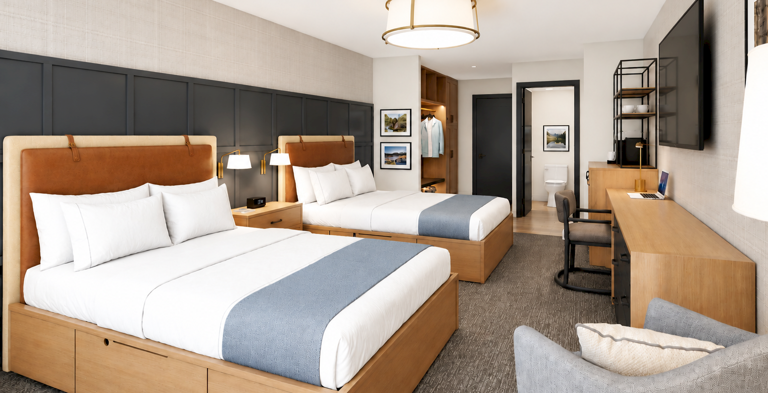 A modern hotel suite with two beds, bedside lamps, a desk, wall TV, and an open bathroom area with a toilet.