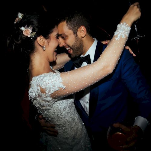 A bride and groom in wedding attire cuddle and dance at night, with the bride&rsquo;s sparkling dress and floral hairpiece.