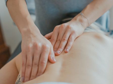 A therapist&rsquo;s hands gently massage a person&rsquo;s shoulder and neck with a soothing touch.